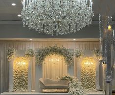 an elegant wedding setup with chandelier and floral arrangements on the wall behind it