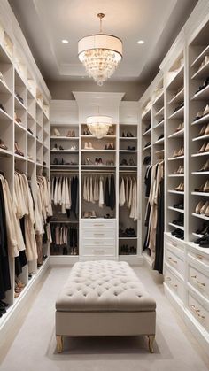 a walk in closet filled with lots of white shelves and clothes on top of drawers