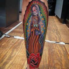 a woman's leg with an image of the virgin mary and roses on it