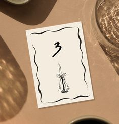 a card with the number three on it sitting next to some cups and saucers