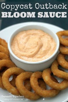 a white plate topped with onion rings next to a small bowl of dip and text that reads copycat outback bloom sauce