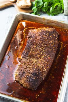 a piece of meat sitting on top of a pan covered in sauce and parsley