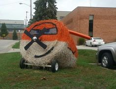 an orange and white ball sitting on top of a grass covered field next to a truck