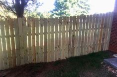 a dog laying on the ground in front of a wooden fence