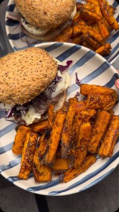 two plates with sandwiches and sweet potato fries on them, one is cut in half