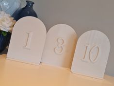 three white wooden numbers sitting on top of a table next to a vase with flowers