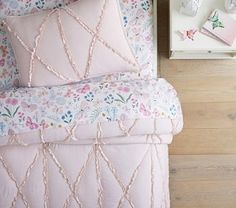 a bed with pink sheets and pillows on top of it next to a wooden wall