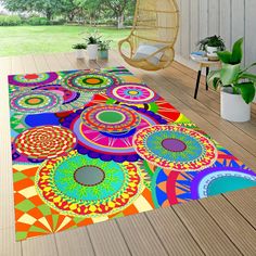 an outdoor area rug with colorful circles on it and a hanging chair in the background