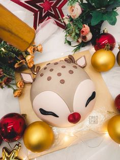 a christmas decoration with ornaments around it and a deer mask on the table next to it