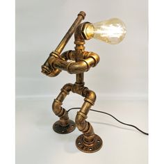 an old fashioned lamp with a light bulb on it's head and arms, made out of brass pipes