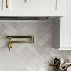 a kitchen with white cabinets and gold handles on the wall above the stove hood, is shown