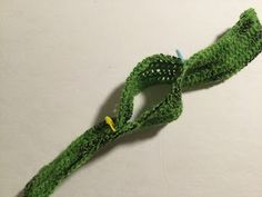 a crocheted green object on a white surface