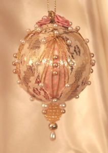 a glass ornament hanging from a chain on a white cloth covered background with beads