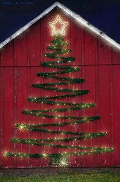 a red barn with a christmas tree on the side and lights in the shape of stars