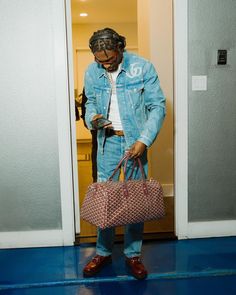 a man holding two bags in his hands and looking at something on the floor next to him