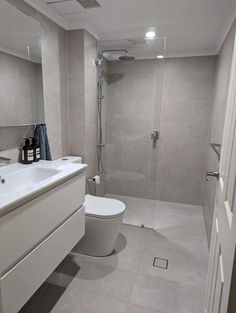 a white toilet sitting in a bathroom next to a walk - in shower and sink