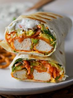 a burrito cut in half sitting on top of a plate next to pretzels