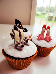 two cupcakes with high heels and bows on them sitting on top of a table