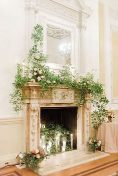 the fireplace is decorated with greenery and candles for an elegant touch to the room