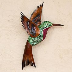 a metal humming bird mounted to the side of a wall with its wings spread out