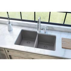 a double sink with two faucets on the counter top next to a window