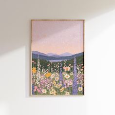 a painting hangs on the wall above a bed with flowers and mountains in the background