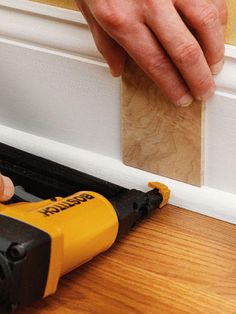 a person using a power drill to attach a piece of wood on the floor in front of a door