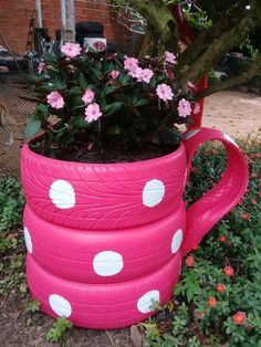 a potted planter made out of old tires is sitting on the ground next to some flowers