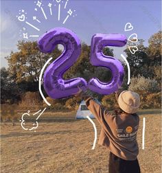 a boy holding up the number twenty five purple balloons