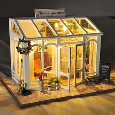 a doll house is lit up with christmas lights and decorations on the outside, including windows