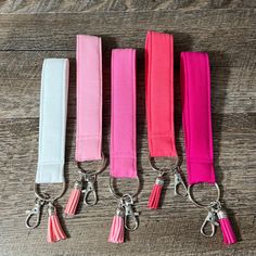 four pink and white lanyards are lined up on a wooden surface with one tied down