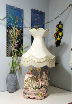 a lamp sitting on top of a table next to a vase and potted plant