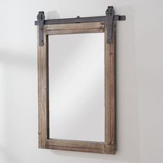 a mirror hanging on the wall next to a wooden frame and metal fittings,