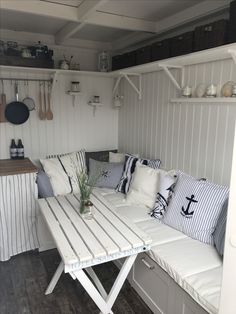 a white couch sitting under a window next to a wooden table