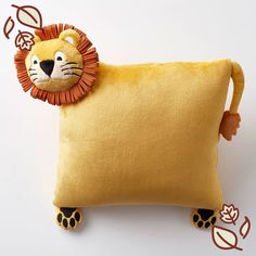 a yellow pillow with a stuffed lion on it's side, sitting against a white background