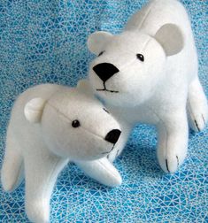 two stuffed polar bears sitting next to each other on a blue surface with an eye patch