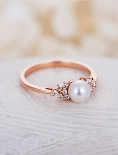 a pearl and diamond ring sitting on top of a table