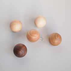 three wooden knobs and two wood balls on a white surface