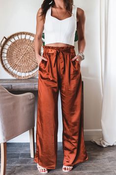 Step into the season with some serious style! Our Jade Wide Leg Pants will take your look from summer to fall with ease. Plus, you can mix and match these pants with any top for endless stylish possibilities! Wear 'em to work, on an errand, to dinner, anywhere! 97% Polyester 3%Spandex Satin Like fabric Color: Deep Rust High waisted Pants Light weight Straight Leg Half Elastic waist band Half front self tie sash (non-removable) Side Pockets No button or zipper closure True to size Model is wearin Colorful Pants Outfit, Satin Pants Outfit, Flirty Fashion, Satin Wide Leg Pants, Mom Outfits Fall, Satin Pants, Summer To Fall, Colored Pants, Mom Outfits