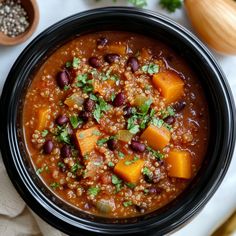 a black bowl filled with beans and other food on top of a white tablecloth