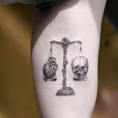 a person with a tattoo on their arm that has a scale and skulls on it