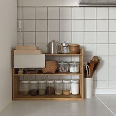 a kitchen with white tile and wooden shelves filled with utensils, coffee mugs and other items