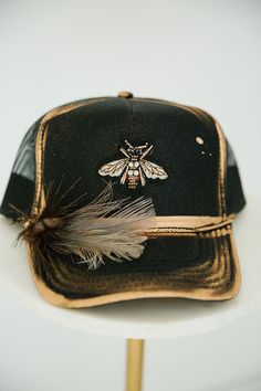 GOLDEN BEE BLACK TRUCKER HAT TRUCKER HAT Judith March Black And White Feather, Indian Hat, Hat Bar, Black Trucker Hat, Cowboys And Indians, Unique Hats, Gold Bee, White Feather, White Feathers