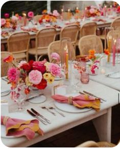 the table is set with pink and orange flowers