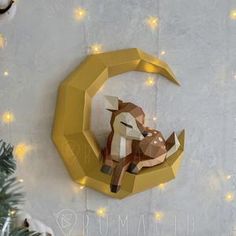 an origami deer sitting on top of a crescent shaped clock with lights around it