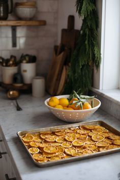 a pan filled with oranges sitting on top of a counter next to a bowl of fruit