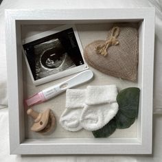 an image of a baby's diaper and accessories in a shadow box on a bed