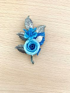 Flower brooch in cold porcelain and polymer, blue flowers and silver foliage: the brooch is made of a branch of foliage in silver-plated brass, 7.5 cm high by 5.6 cm wide. On the branch, flowers of cold porcelain and sky blue and petroleum blue polymer clay are attached. A petrol blue leaf and a silver leaf complete this pretty bouquet. A very pretty brooch to decorate a jacket lapel, attach a scarf.... or a nice gift idea! To see the perfectly matched earrings, follow this link: https://www.etsy.com/fr/listing/1269815519/boucles-fleurs-bleues-roses-en-pate?click_key=86d26fdade4885c817f3cae0fd0836ab0d23dadb%3A1269815519&click_sum=b38d8631& ref= shop_home_active_350&sca=1&sts=1 All my jewelry is packaged with care, and delivered in tracked parcel or international tracking. I communicate the Petroleum Blue, Blue Polymer Clay, Pretty Bouquet, Polymer Flowers, Prettiest Bouquet, Petrol Blue, Blue Leaves, Cold Porcelain, Flower Brooch