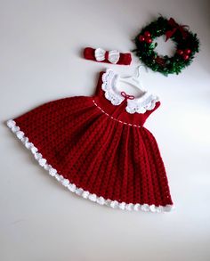 a crocheted dress and headband with a wreath on the table next to it