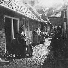 an old black and white photo of people walking down a cobblestone street